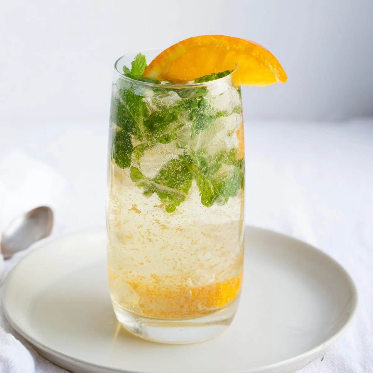 Close-up of a refreshing Probiotic Soda Mocktail garnished with orange slices and mint.  