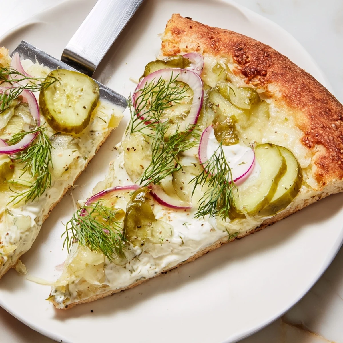 Tangy Pickle Pizza with creamy sauce, mozzarella, and crunchy dill toppings.  