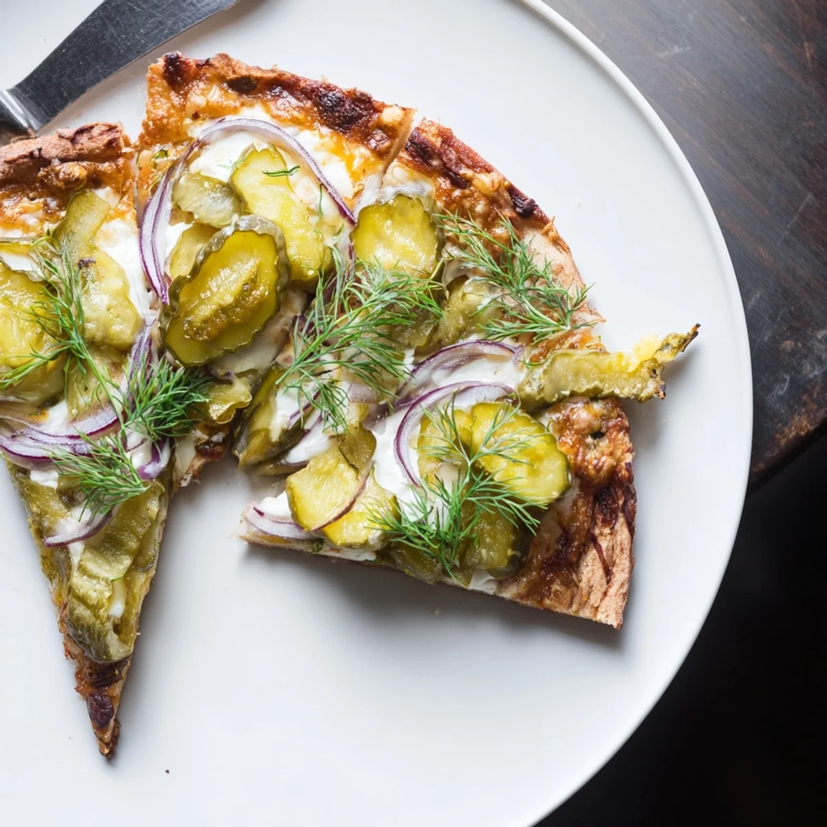 Savory Pickle Pizza drizzled with crème fraîche, topped with fresh dill and onion.