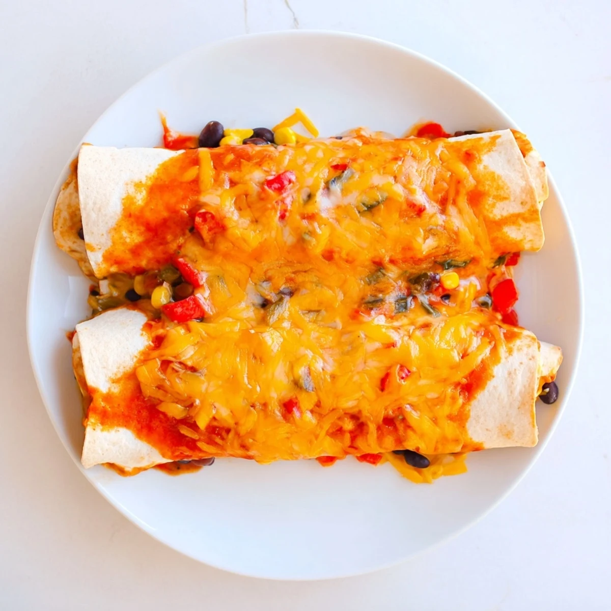 Warm and cheesy Farmers Market Vegetarian Enchiladas, baked in a rich red sauce, garnished with fresh cilantro.
