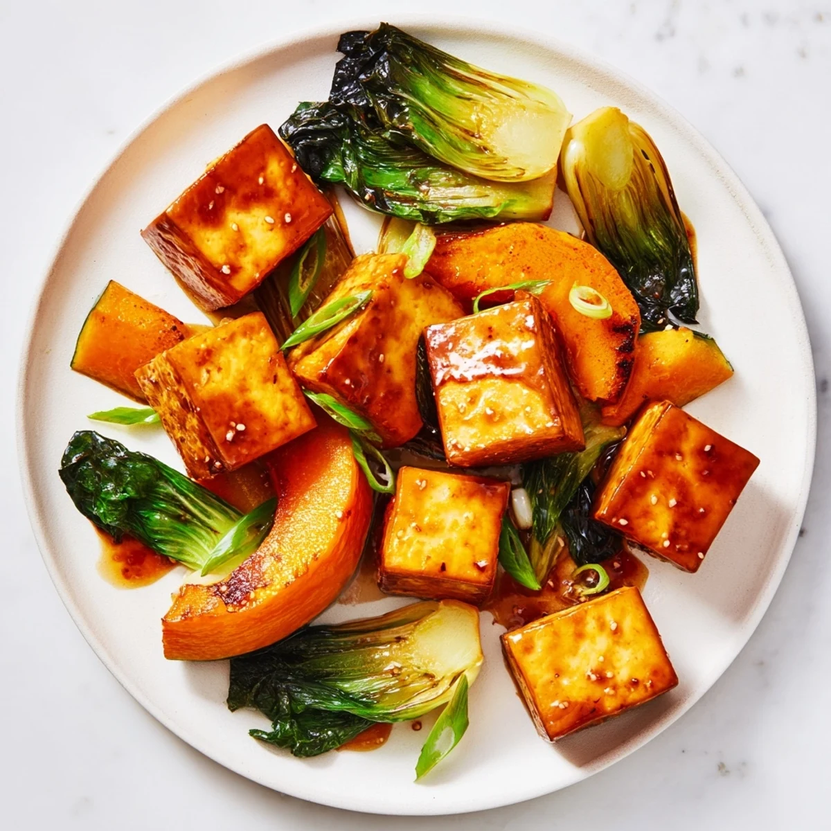 Golden-brown miso-glazed tofu and winter squash alongside tender green bok choy, a delicious vegan dish.
