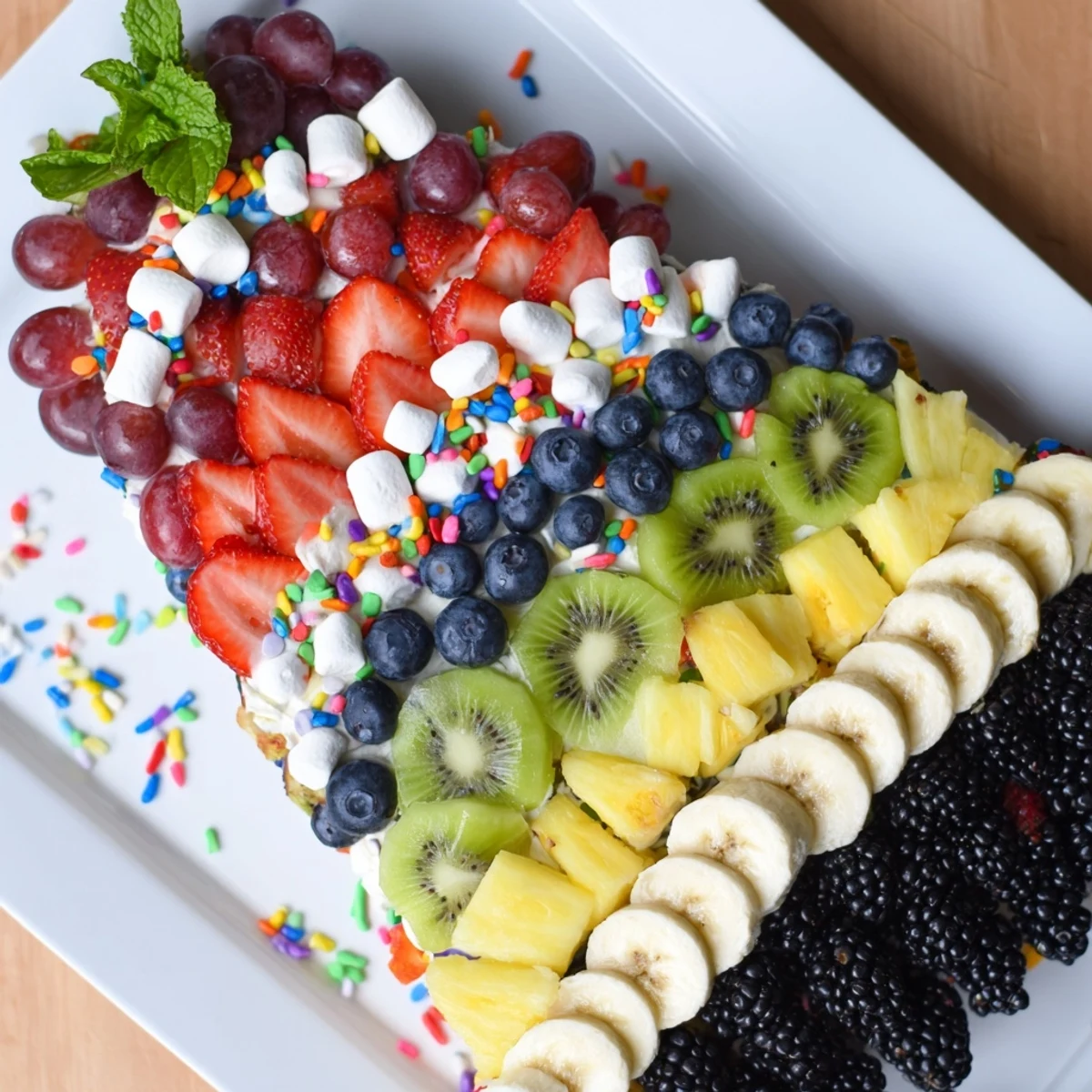 Festive happy birthday cake slice fruit board with colorful berries and pineapple for a party.
