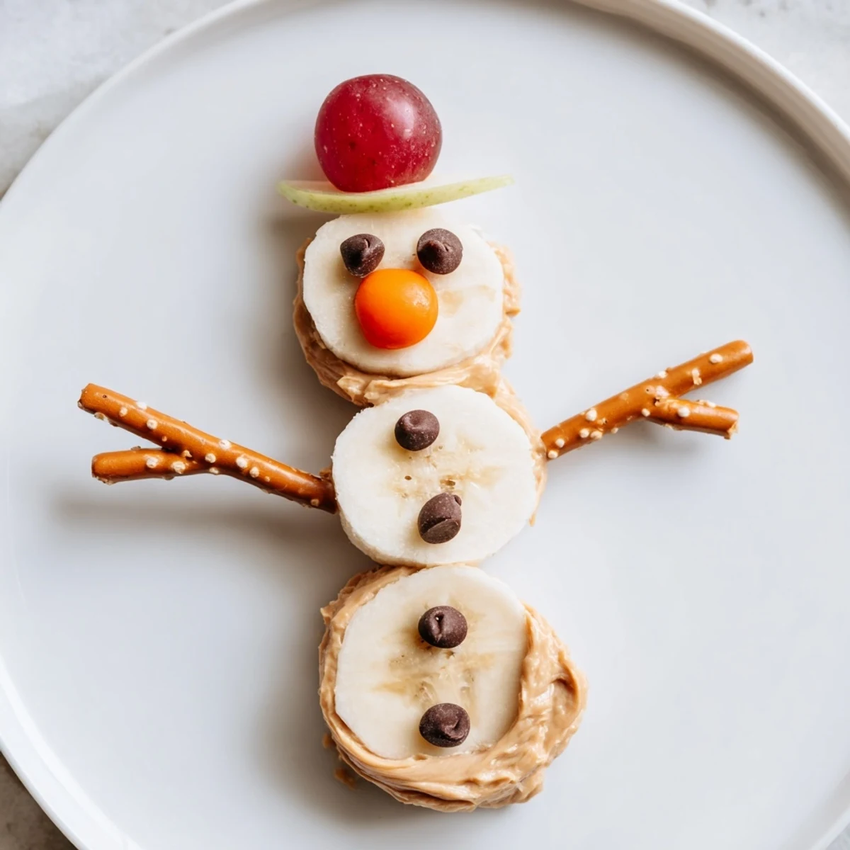 These yummy Banana Peanut Butter Snowmen feature pretzel arms, perfect for a healthy treat.
