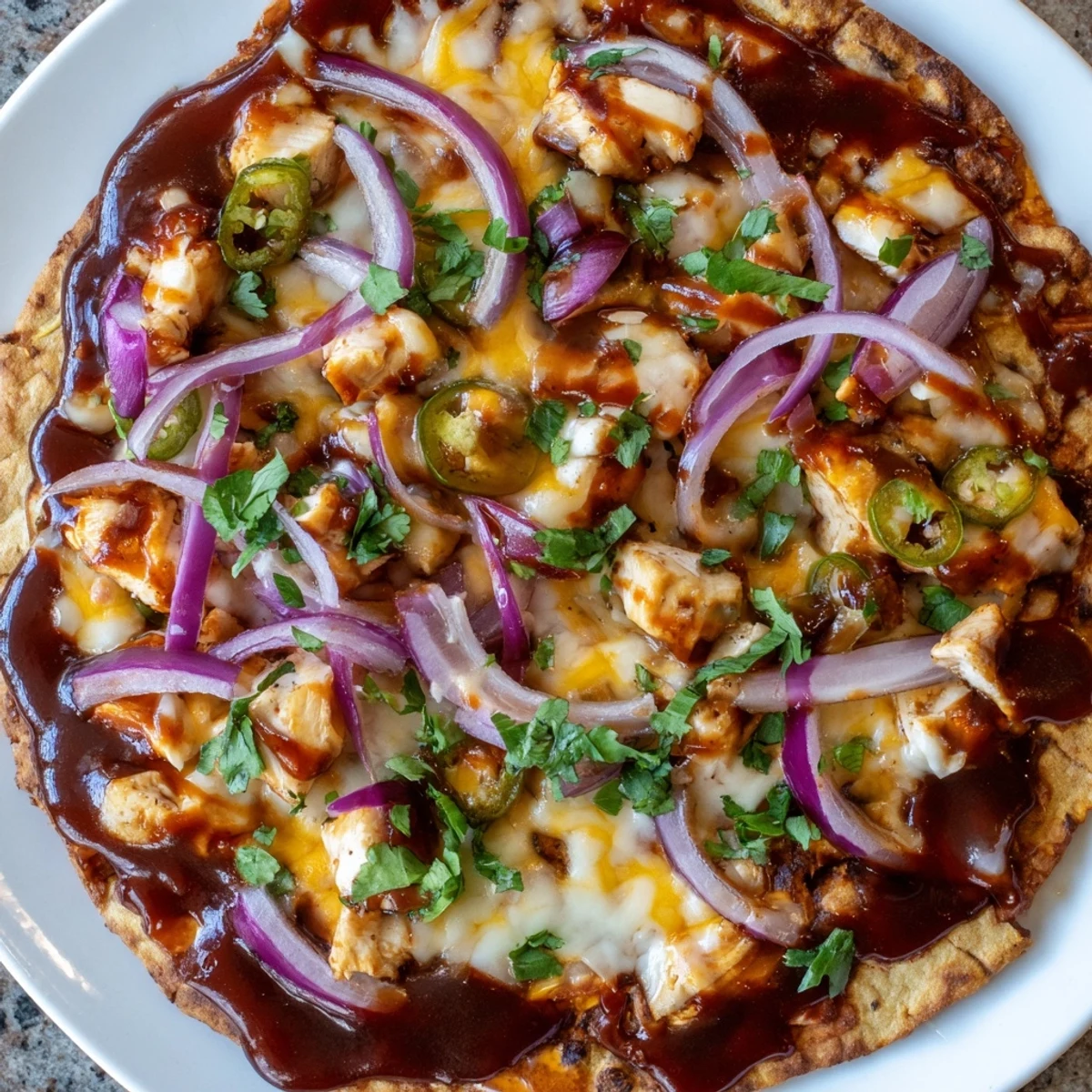 A close-up of a bubbling BBQ Chicken Flatbread with melty cheese, pulled chicken, and red onion.