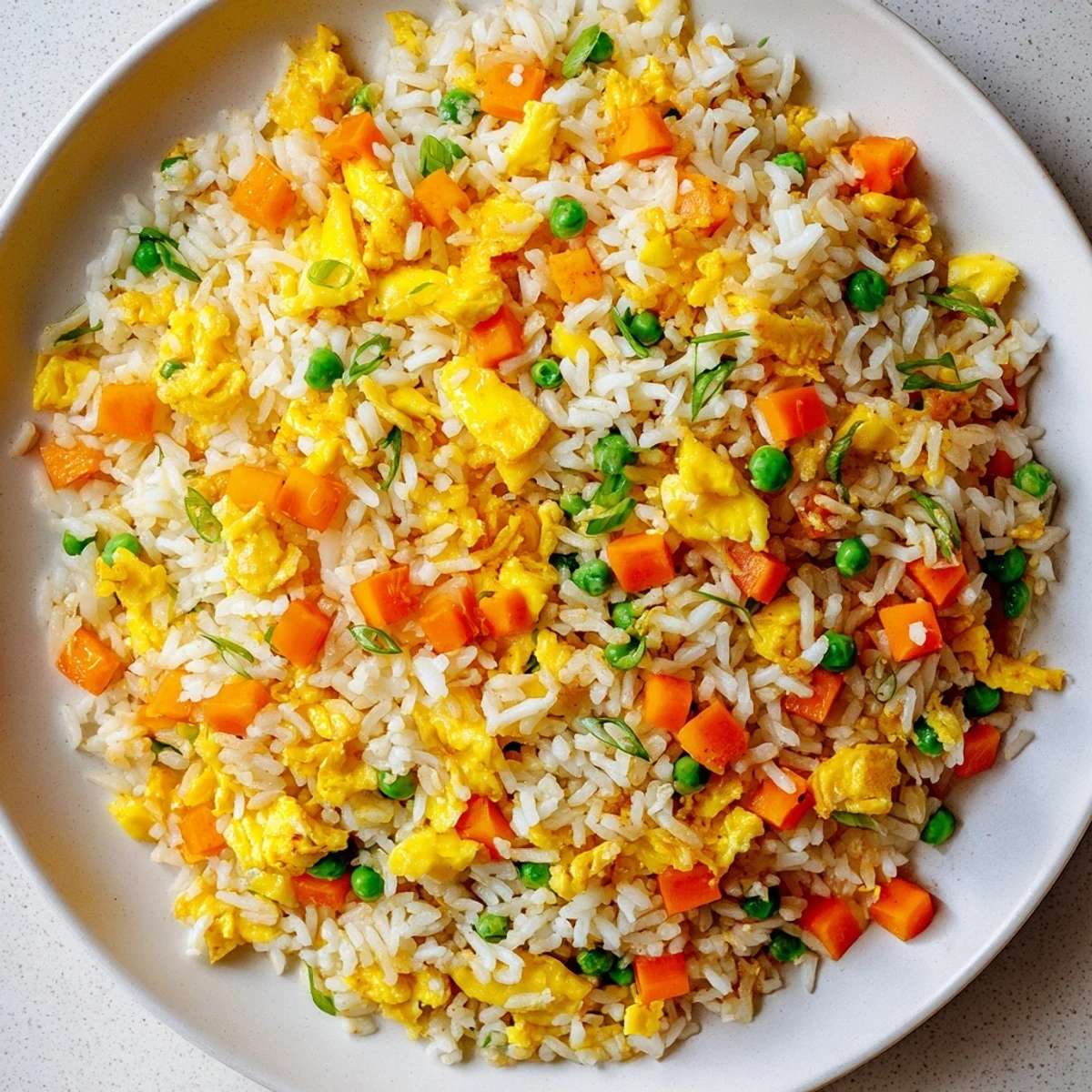 Fluffy scrambled eggs and vibrant peas and carrots in classic Egg Fried Rice, served steaming hot in a bowl.  