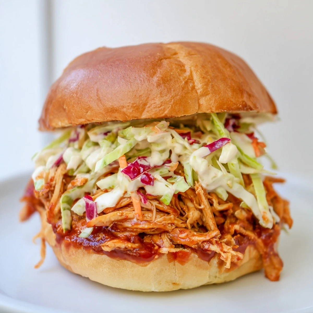 Tender, slow-cooked pulled barbecue chicken nestled in a soft bun, ready to be devoured.