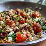 In a large skillet, Mediterranean Keto Ground Chicken Skillet with Olives and Feta is tossed with briny Kalamata olives and wilted baby spinach.