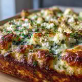 A slice of High Protein Spinach Artichoke Bake on a white plate, showing creamy texture with visible spinach and artichoke chunks.
