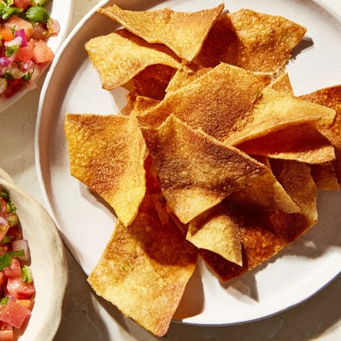 Golden air-fryer tortilla chips sit next to a vibrant bowl of homemade, fresh salsa.