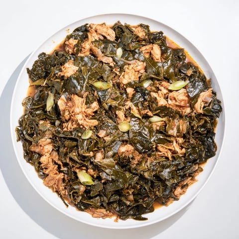 Tender Southern-style collard greens with smoky turkey, served steaming hot in a rustic bowl.