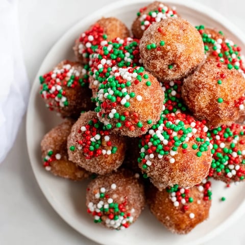 Golden air fryer Christmas donut holes topped with colorful holiday sprinkles, ready to enjoy.
