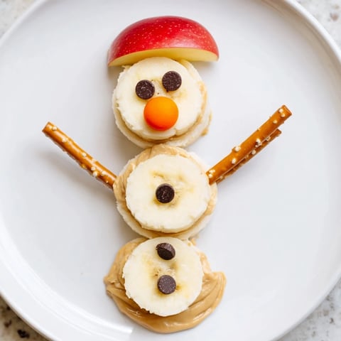 Adorable Banana Peanut Butter Snowmen arranged with creative decorations on a festive plate.