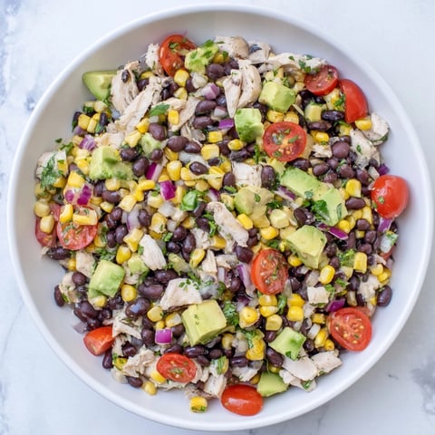 Hearty bowl of Dense Southwestern Bean Salad, a colorful mix of beans, corn, and chicken.