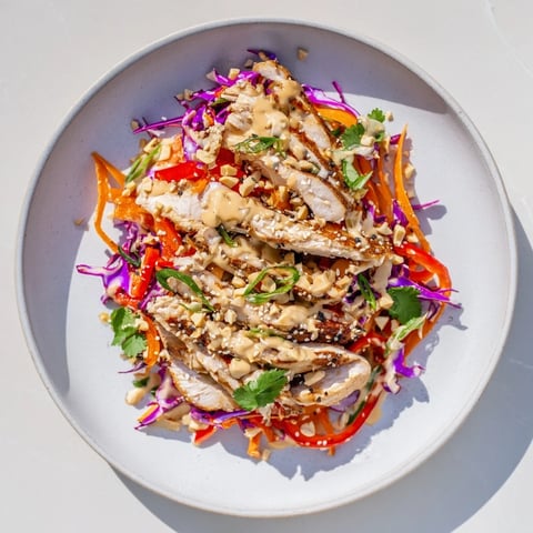 A colorful bowl of Carrot Ribbon and Chicken Slaw, ready to eat with a creamy ginger-miso dressing.