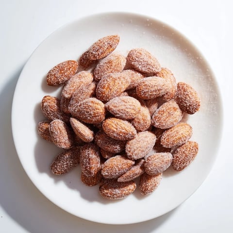 Golden and glistening cinnamon roasted almonds piled on a baking sheet, tempting snack.