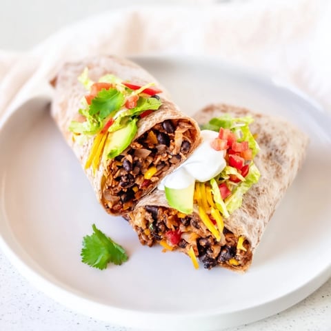 Steaming Smoky Black Bean Burrito, overflowing with colorful veggies and creamy avocado, ready to eat.