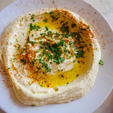 Creamy Levantine Hummus Plate drizzled with olive oil, ready to scoop with warm pita bread.