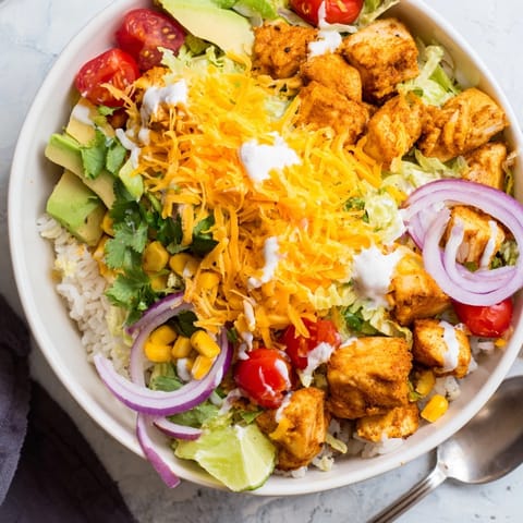 A colorful scoop of Cheesy Cajun Fish Taco Bowls, lime wedge for extra zest.