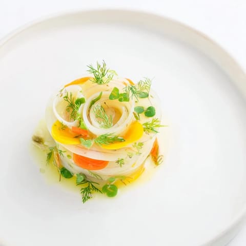 A visually striking presentation of The Spinning Top salad, ready to be drizzled with lemon vinaigrette.