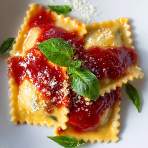 Tender Spinach Ricotta Ravioli plated with a rich tomato sauce and grated Parmesan for a comforting Italian meal.