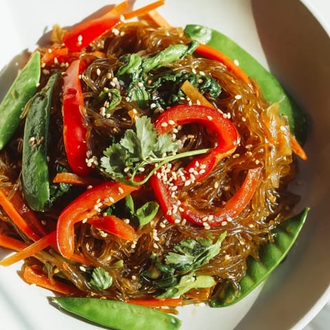 This vegan kelp noodle stir-fry in a white bowl features julienned carrot and fresh cilantro garnish.