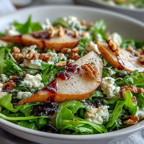 Freshly tossed Arugula and Pear Bowl featuring ripe pear wedges, crumbled goat cheese, and a light honey balsamic drizzle.