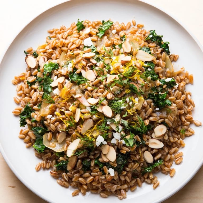 This image shows a beautifully plated Warm Farro & Greens Pilaf, garnished with toasty almonds.