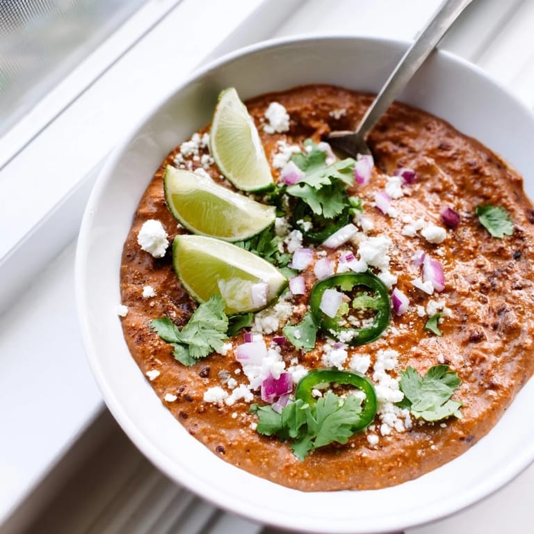 Vegan Spicy Black Bean Dip served with crunchy vegetable sticks and warm tortilla chips on a wooden table.